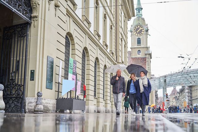 Drei Personen gehen ins Berner Generationenhaus, im Hintergrund ist der Bahnhofsplatz zu sehen