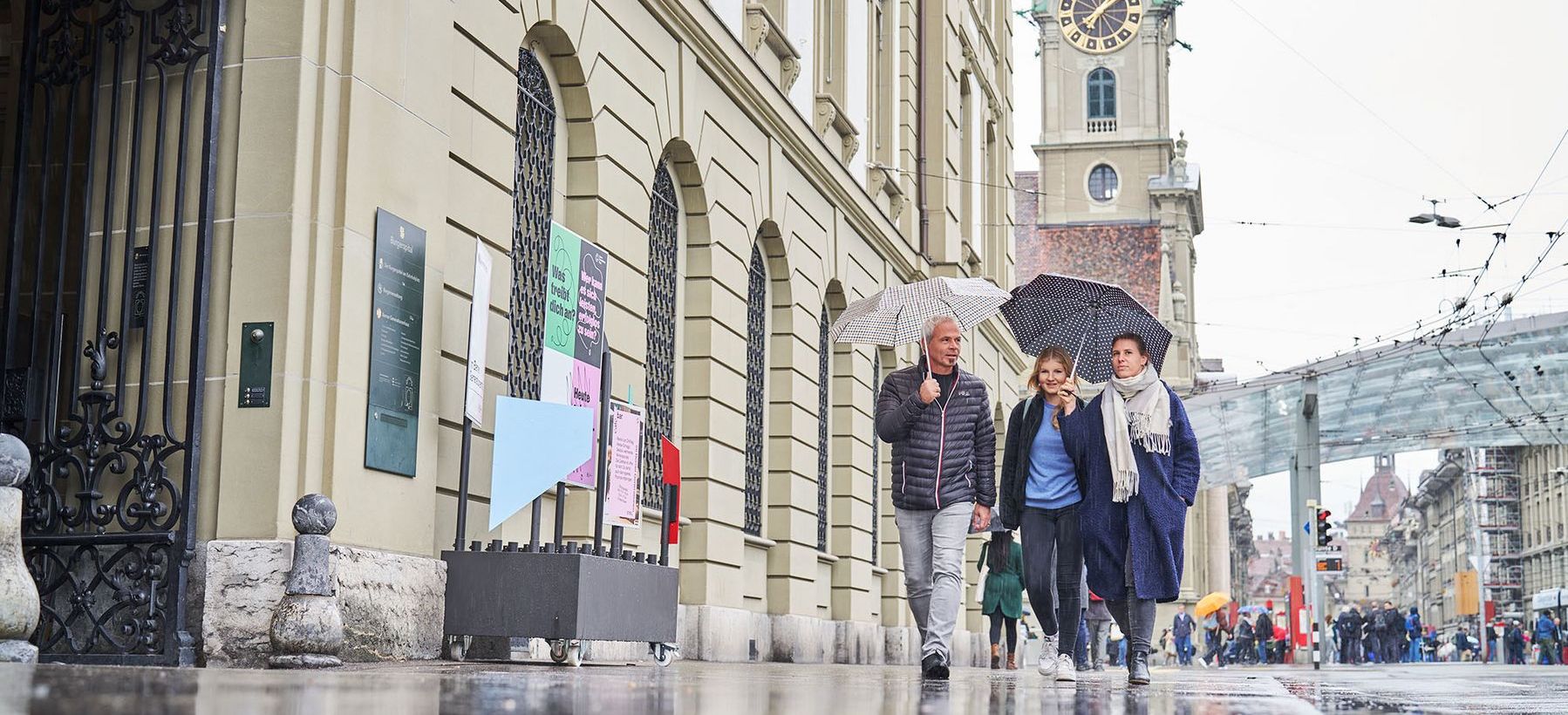 Drei Personen gehen ins Berner Generationenhaus, im Hintergrund ist der Bahnhofsplatz zu sehen