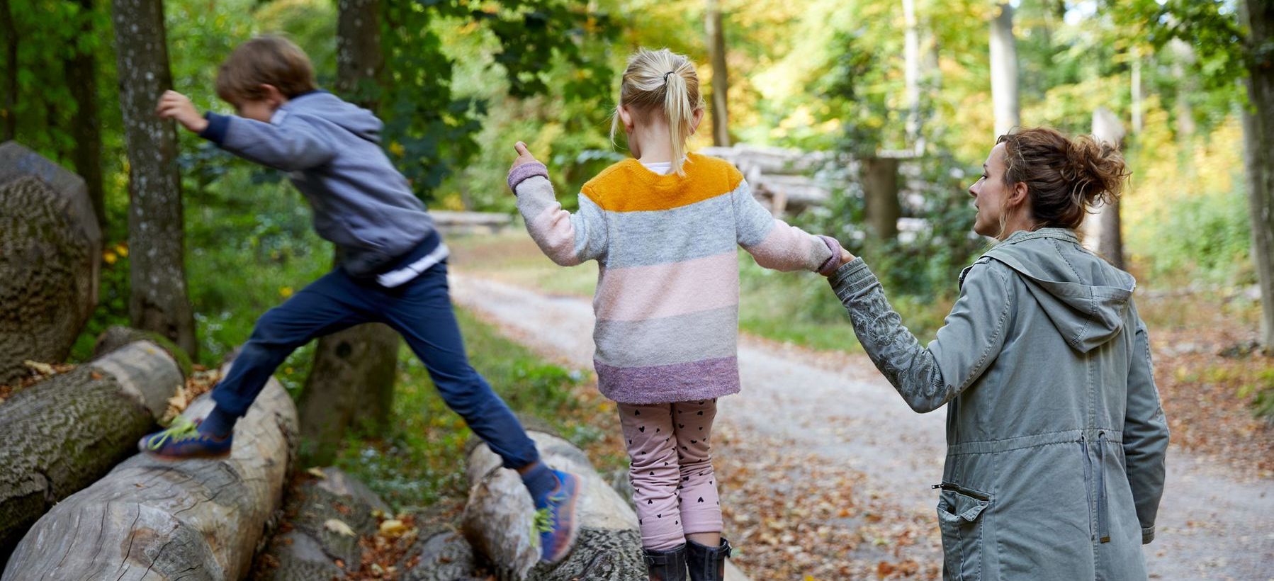 Eine Mutter spaziert mit Kindern im Wald