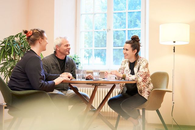 Zwei Personen sitzen an einem Beratungsgespräch mit einer Fachperson vom Eltern Walk-in
