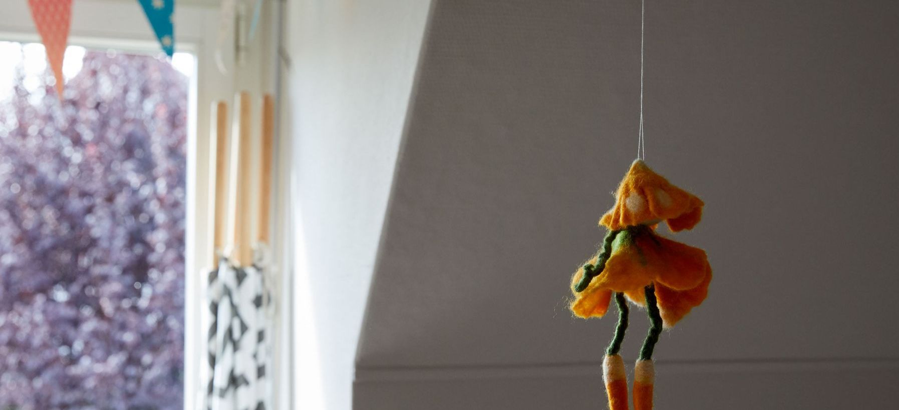 Eine Filzfigur hängt von der Decke eines Kinderzimmers