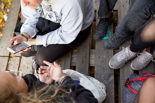 Jugendliche sitzen auf einer Palette und unterhalten sich