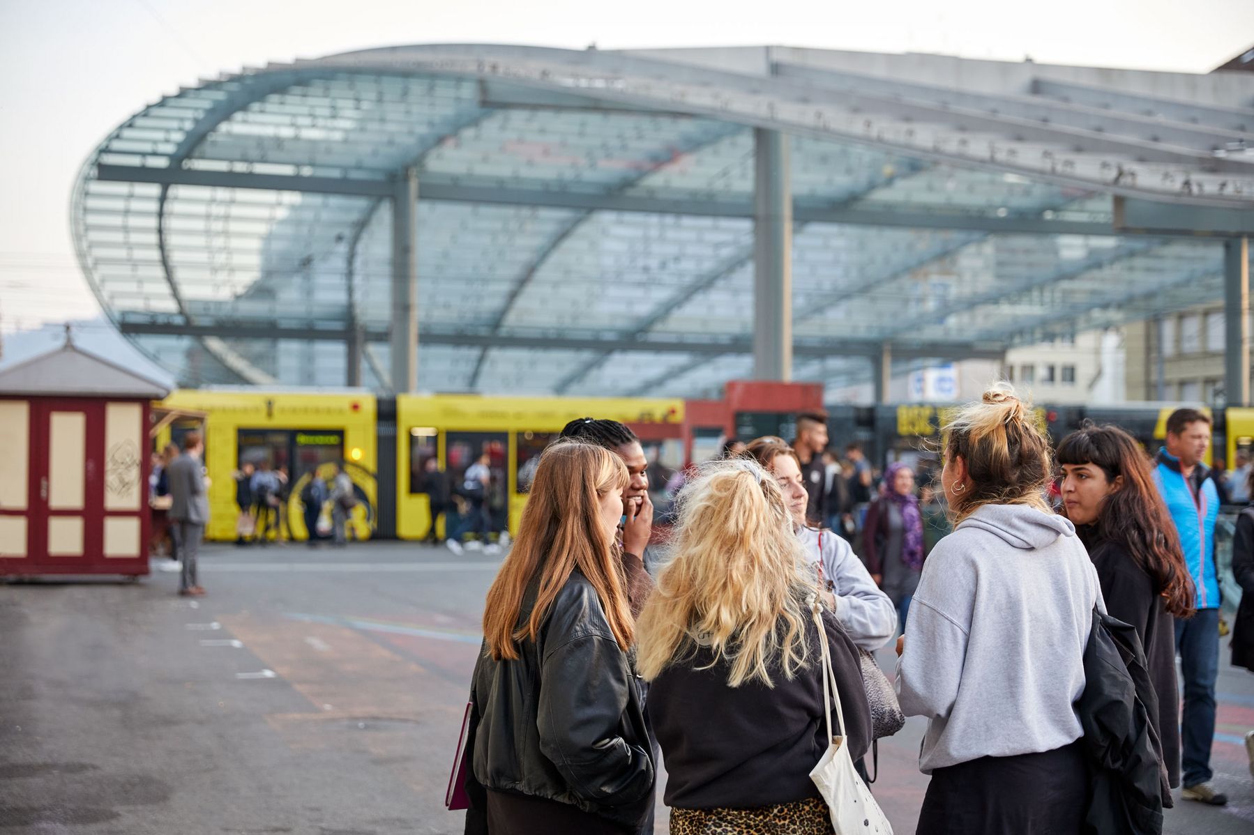 Jugendliche stehen in einer Gruppe auf dem Bahnhofsplatz und unterhalten sich