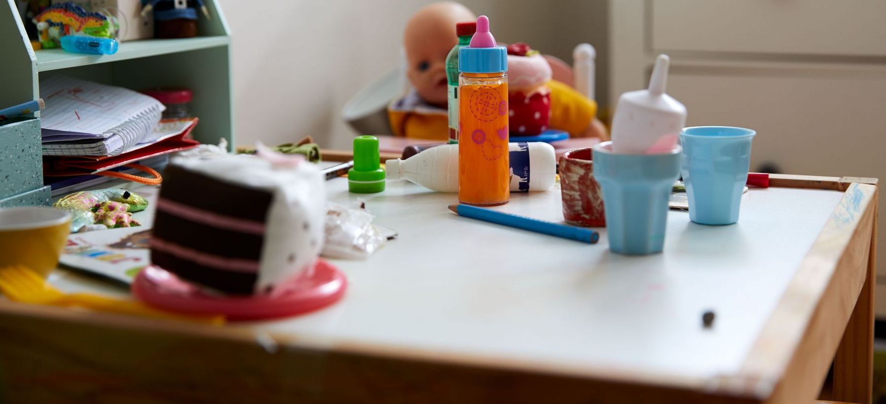 Ein Kinderzimmer mit Tisch, Spielzeug und Bastelmaterial